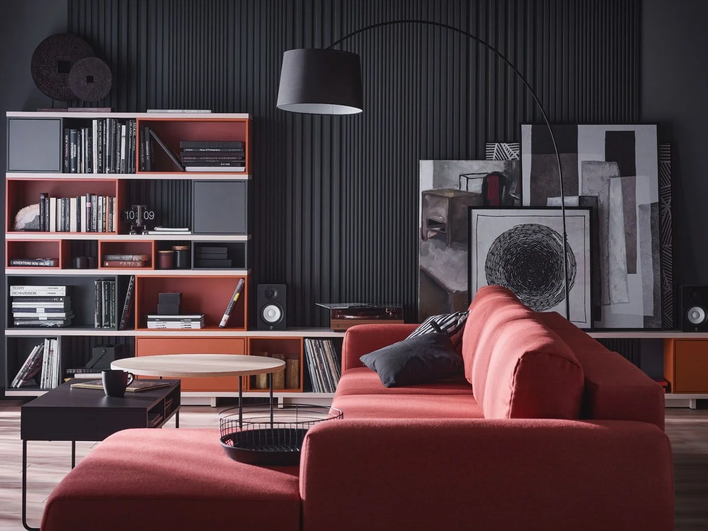 Salon z ceglastą sofą i czarną ścianą z półkami 
